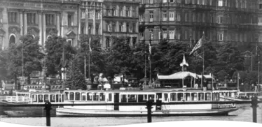 Historisches Schwarz-Weiß-Foto eines großen Alsterdampfers, der vor dem Rathausufer in Hamburg angelegt hat.