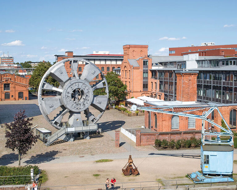 Hof des Museums der Arbeit in Barmbek mit den roten Backsteinbauten und einem großen Schaufelrad.